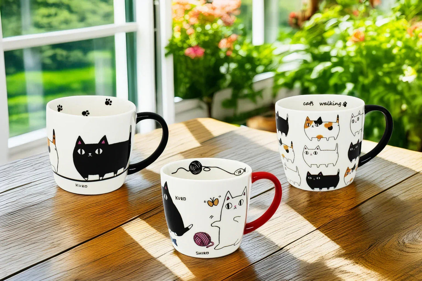 Three 3 Cat Brothers Porcelain Mugs from Japan’s Nyan-ya Series displayed on a wooden dining table, featuring designs Marching Cats, Cat Parade Traffic Jam, and Favorite Foods with Kuro, Shiro, and Mike. In the background, a sunlit window with green plants and blooming flowers adds a cozy, cheerful atmosphere.