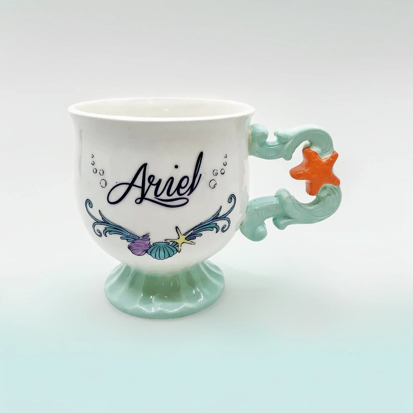 Ariel The Little Mermaid porcelain mug with colorful artwork and Disney gift box. Styled on white background with front and back views.