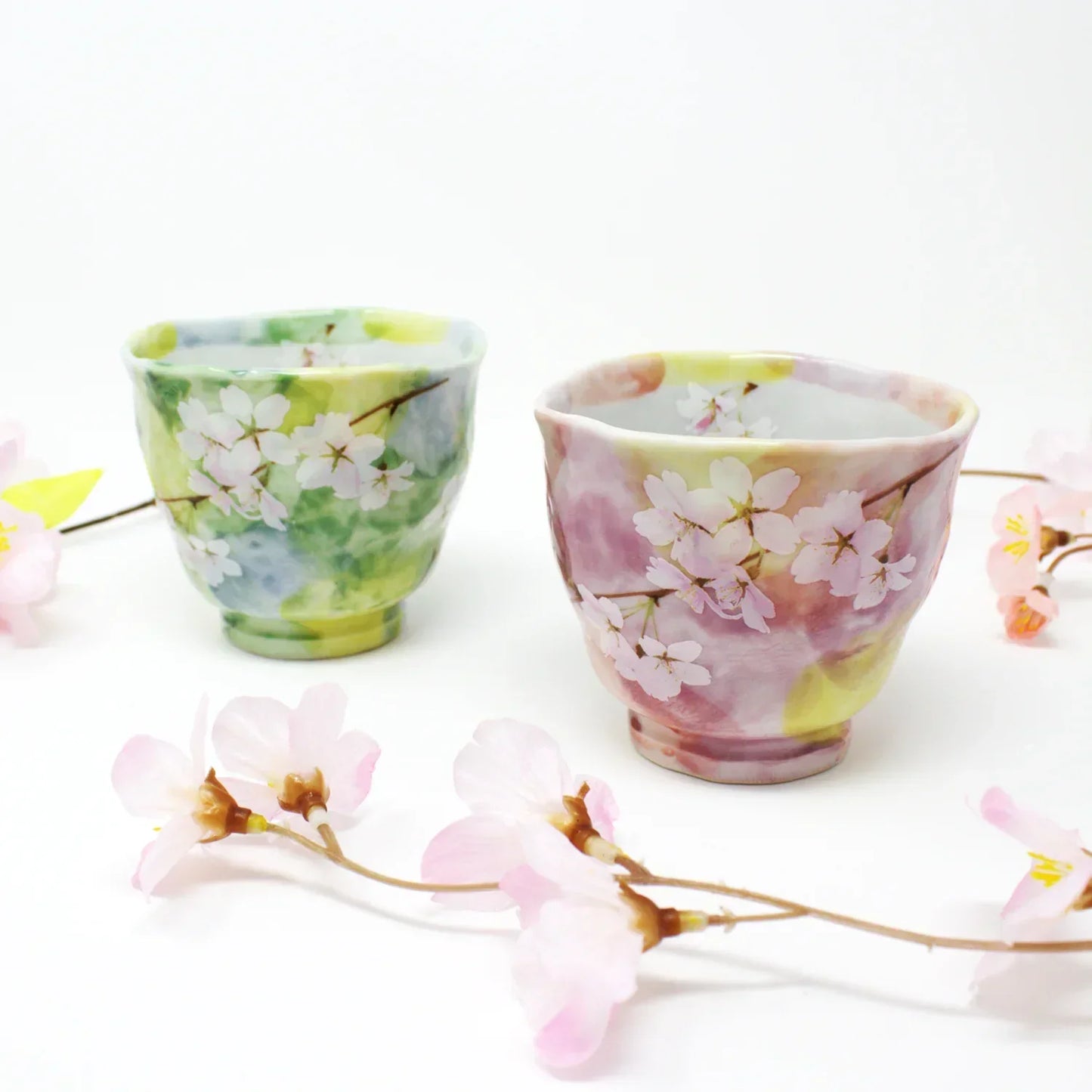 Side view of Hanagasumi Mino Ware Yunomi teacup featuring soft pink and yellow hues with delicate cherry blossom branches, made in Japan.