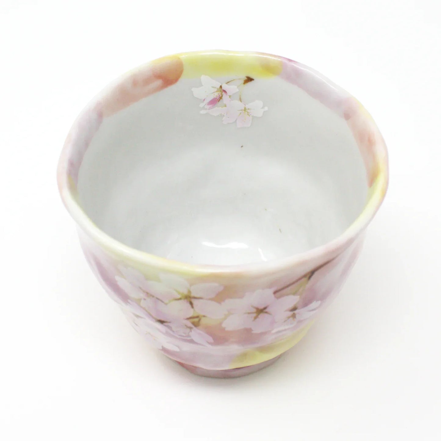 Top view of handcrafted Japanese Yunomi teacup showcasing smooth porcelain interior and subtle pink floral design.