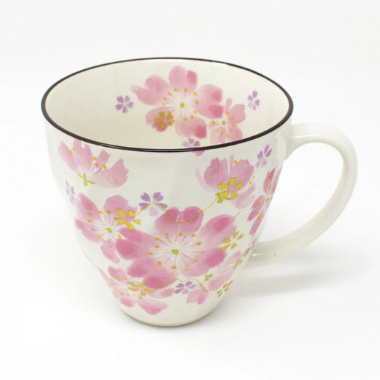 Side view of a Japanese cherry blossom ceramic mug with delicate pink and white floral sakura design, placed next to its chirimen fabric coaster and wooden gift box. Made in Japan, perfect for gifting.