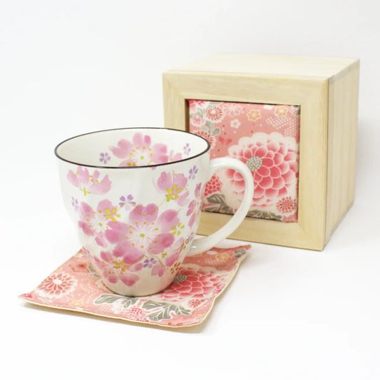 Japanese cherry blossom mug gift set featuring a pink sakura ceramic mug, chirimen fabric coaster, and wooden gift box. The mug is styled with floral details and springtime ambiance, perfect for tea lovers or Mother's Day gifts.