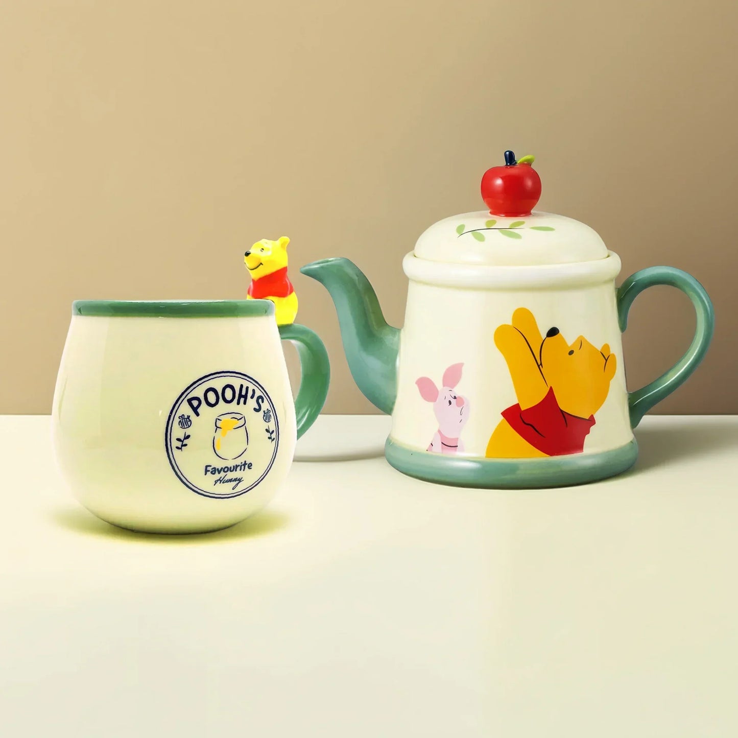 Winnie the Pooh porcelain mug with figurine handle and matching apple-themed teapot on wooden surface, warm cozy background – Disney collectible gift set