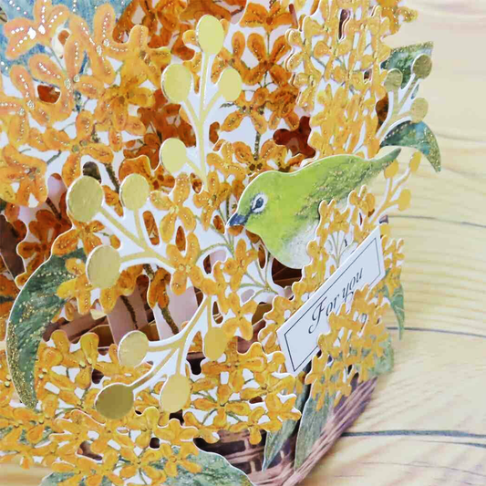 Decorative pop up card with floral design and bird illustration on a wooden surface