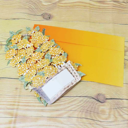 Yellow flowers in a wicker basket on an orange envelope with a wooden background