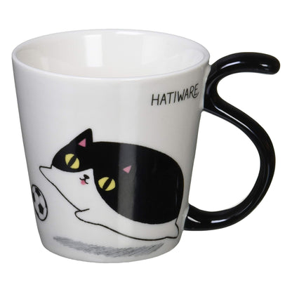 Porcelain mug featuring Hachiware the tuxedo cat chasing a soccer ball with a black tail-shaped handle
