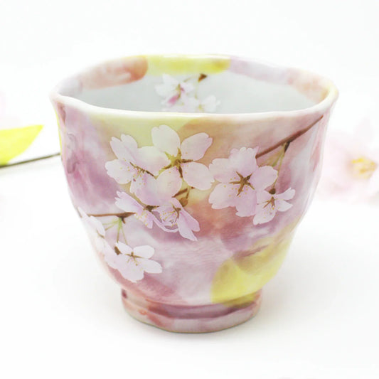 Side view of Hanagasumi Mino Ware Yunomi teacup featuring soft pink and yellow hues with delicate cherry blossom branches, made in Japan.