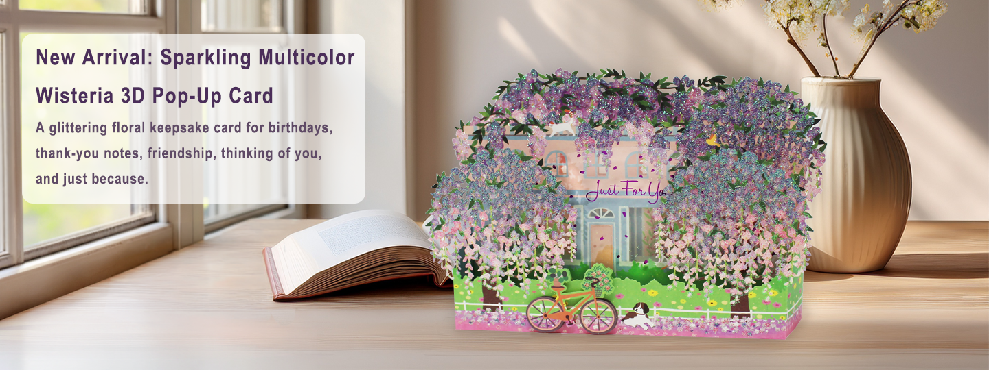 Multicolor Wisteria 3D Pop-Up Card on a wooden surface with a vase and flowers in the background.