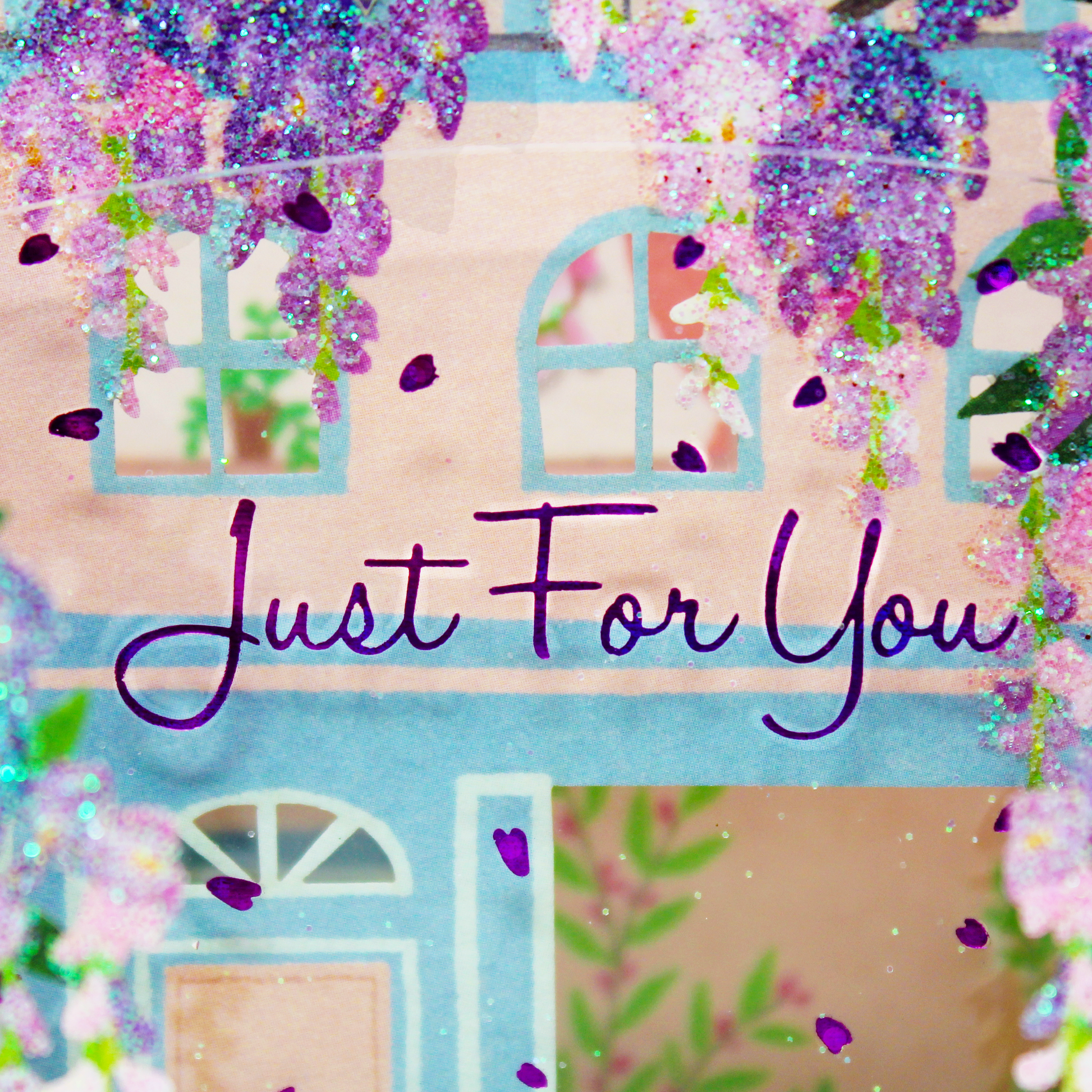 Close up of the clear plastic layer with holographic foil petals and Just For You message